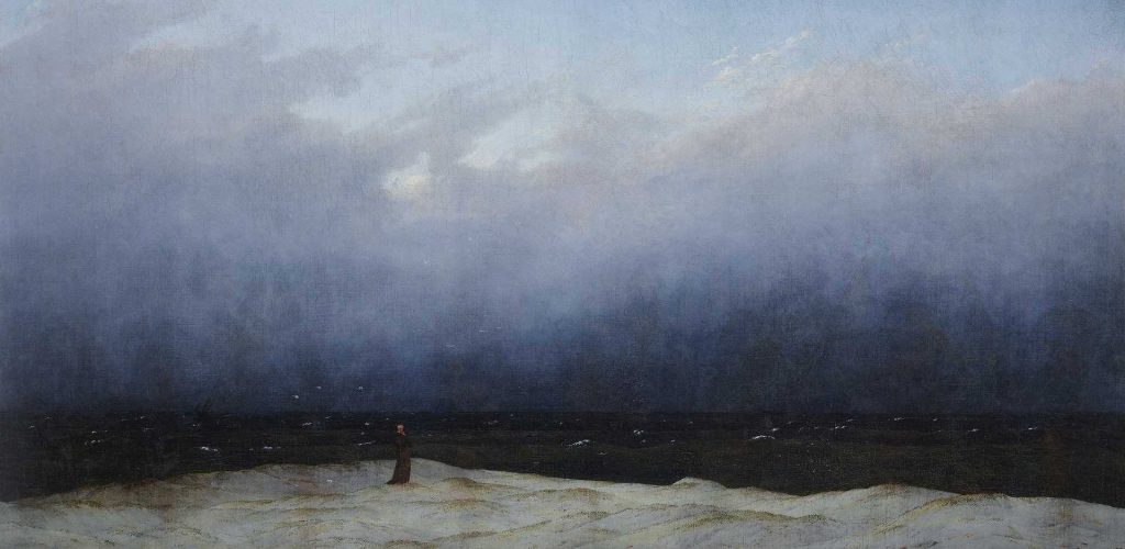 A figure standing on a sandy beach, gazing toward a dark, stormy sea under a cloudy sky, evoking a sense of solitude and contemplation.